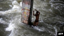Seorang anak laki-laki bermain di bawah jembatan di Manila, Filipina, usai topan Sarika melanda Pulau Luzon di sana (16/10). (AFP/Noel Celis)