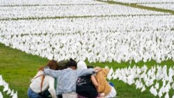 Visitors sit among white flags that are part of artist Suzanne Brennan Firstenberg's temporary art installation to commemorate Americans who have died of COVID-19, on the National Mall in Washington, Sept. 21, 2021.