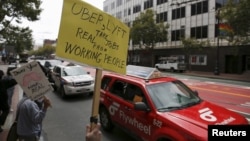 Members of the San Francisco Taxi Workers Association carry signs at a rally at Uber headquarters in San Francisco, California, June 22, 2015.
