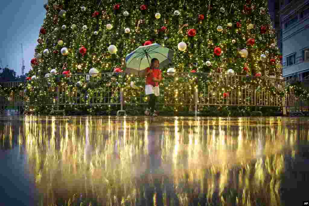 A young girl walks in front of a Christmas tree at a mall in Kuala Lumpur, Malaysia.
