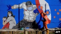 Seorang petugas tengah menggambar mural dengan pesan kampanye melawan virus Covid-19 di Jakarta, 27 Agustus 2020. (Foto: dok)