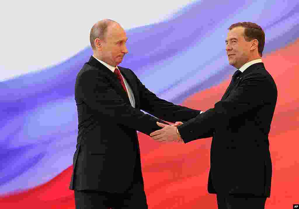 Russian President Vladimir Putin, left, and former President Dmitry Medvedev shakes hands at the inauguration ceremony. (AP)