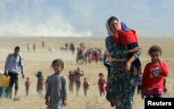 Displaced people from the minority Yazidi sect, fleeing violence from forces loyal to the Islamic State in Sinjar town, walk towards the Syrian border, on the outskirts of Sinjar mountain