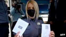 Polisi perempuan di perbatasan Bregana antara Kroasia dan Slovenia menunjukkan paspor COVID digital Uni Eropa, 2 Juni 2021. (Denis LOVROVIC / AFP)
