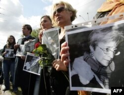 FILE - Ukrainian women hold flowers and portraits during a ceremony to commemorate murdered journalist Anna Politkovskaya, in front of the Russian embassy in Kyiv, Oct. 10, 2006.