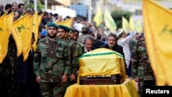 Brothers of top Hezbollah commander Mustafa Badreddine, who was killed in an attack in Syria, mourn over his coffin during his funeral in Beirut's southern suburbs, Lebanon, May 13, 2016