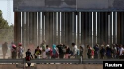 FILE - Migrants queue to request asylum after crossing illegally into El Paso, in this picture taken from Ciudad Juarez, Mexico, April 21, 2019.