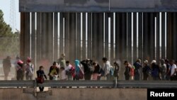 FILE - Migrants queue to request asylum after crossing illegally into El Paso, Texas, in this photo taken from Ciudad Juarez, Mexico, April 21, 2019.