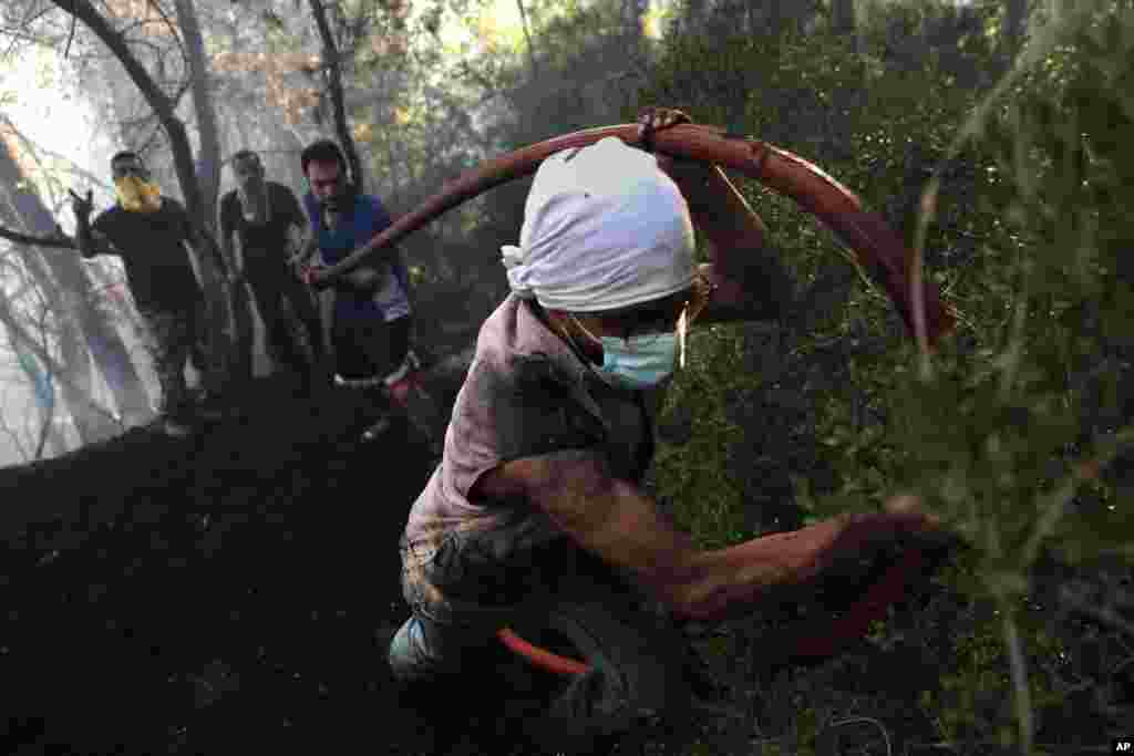 Civil defense workers extinguish a forest fire at Qobayat village, in the northern Akkar province, Lebanon.