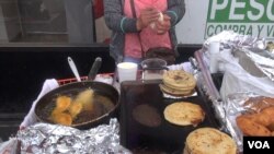 A vendor in Los Angeles prepares pupusas, center, and other savory Salvadoran street food. The city council unanimously voted to decriminalize sidewalk sales. (A. Martinez/VOA)