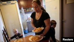 Olga Argyrou prepares to serve lunch to her children at the kitchen of her house at the suburb of Keratsini in Athens, Greece, March 27, 2017. 