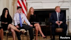 Para pelajar SMU Marjory Stoneman Douglas yang selamat dalam insiden penembakan, Jonathan Blank, dua dari kiri, dan Julia Cordover, ibu Jonathan, Melissa Blank, kiri, mendengarkan Presiden Donald Trump dalam sesi dengar pendapat di Gedung Putih, 21 Februari 2018. 