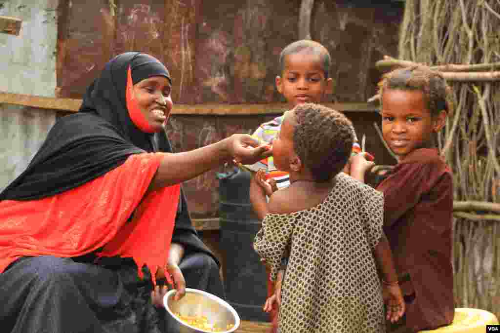 Refugee Habiba Omar Dahir, 28, gives food to children in Kenya’s Dadaab refugee camp on September 19, 2016. (Jill Craig/VOA)