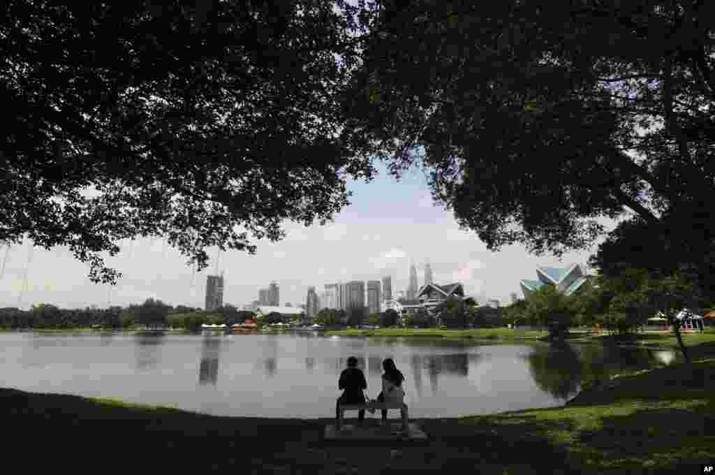 یک زوج مالزیایی پس از یک روز طولانی کاری در مقابل دریاچه پارکی در کوالالامپور استراحت می کنند.