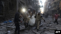 Syrian emergency personnel carry a body following an air strike on November 3, 2015, in the rebel-held side of the northern city of Aleppo.