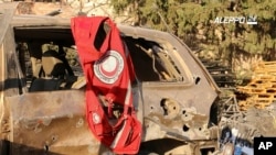 This image provided by the Syrian anti-government group Aleppo 24 news, shows a vest of the Syrian Arab Red Crescent hanging on a damaged vehicle, in Aleppo, Syria, Sept. 20, 2016.