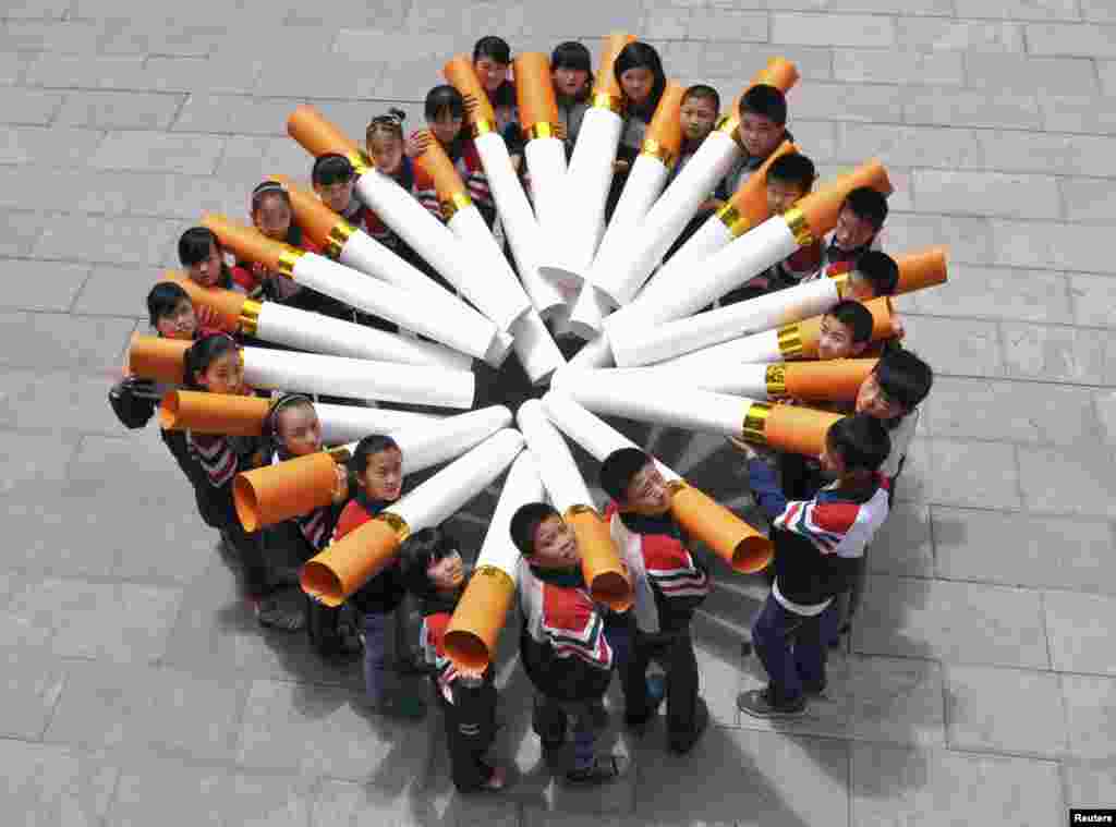 Students pose for pictures with "big cigarette models" during a campaign ahead of the World No Tobacco Day, at a primary school in Handan, Hebei province, China, May 29, 2013. 