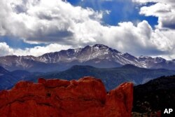 ** FILE** In this May 2, 2006 file photo the sun breaks through the clouds to highlight the summit of Pikes Peak as seen from the Garden of the Gods in Colorado Springs, Colo. (AP Photo/Ed Andrieski, File)