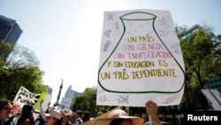 FILE - A demonstrator holds a placard as she participates in the March for Science rally on Earth Day in Mexico City, Mexico April 22, 2017. The placard reads: "A country without science, research and education is a country dependent." Earth Day 2018, which is Sunday, will focus on plastics pollution. 