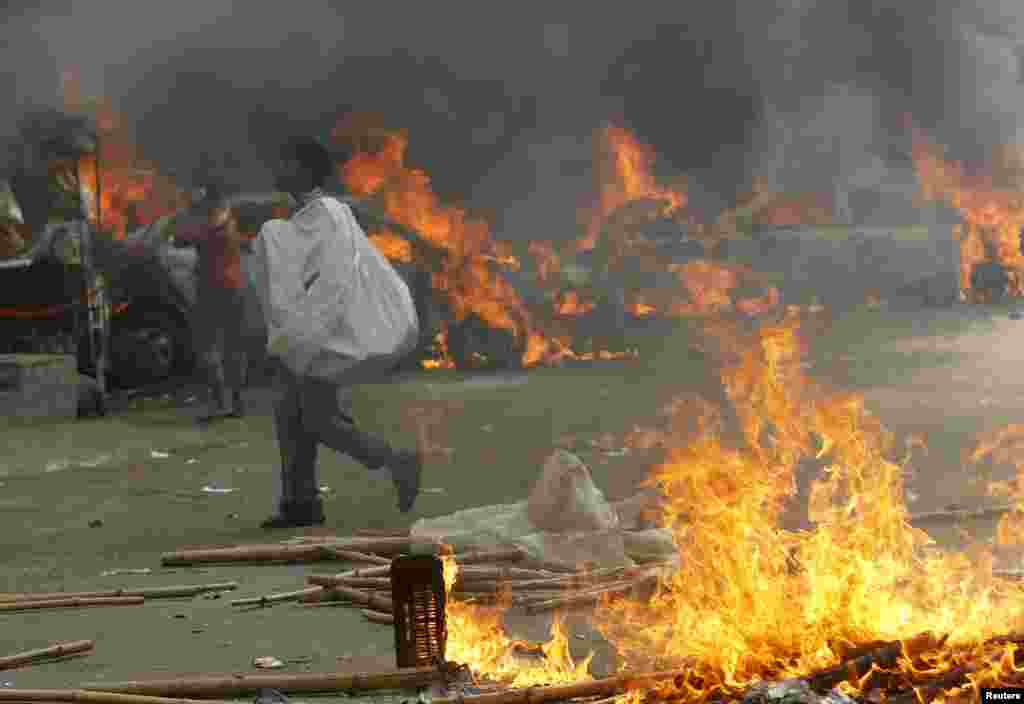 A man walks past vehicles that were set on fire by Jamaat-e-Islami party activists during clashes with police in Dhaka, Dec. 13, 2013.