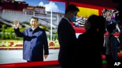 People gather near a display featuring a photo of Chinese President Xi Jinping at the Potala Palace in Beijing, Oct. 20, 2021.