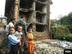Anak-anak Nepal berdiri di depan bangunan yang runtuh akibat gempa yang mengguncang Katmadu, Nepal pada 2011.