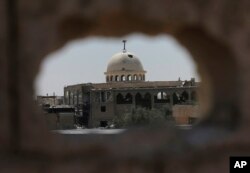 A destroyed mosque is seen through a hole of U.S.-backed Syrian Democratic Forces sniper, on the front line on the eastern side of Raqqa, Syria, July 26, 2017.