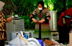 Mantan wali kota Surabaya Tri Rismaharini terlibat dalam aktivitas penyediaan minuman dan makanan tambahan di dapur umum. (Foto: VOA/Petrus Riski)