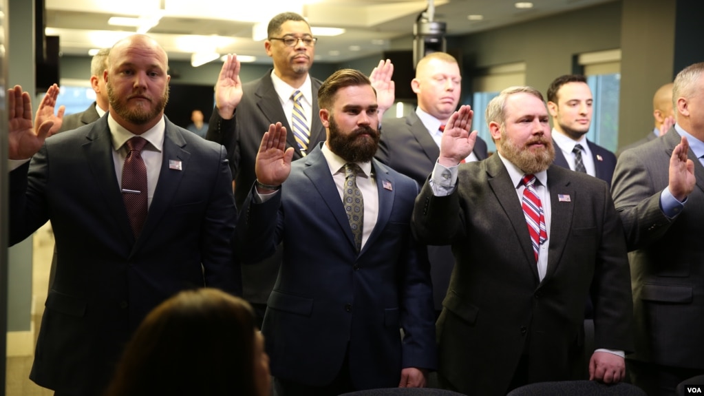 A group of military veterans take the oath at a U.S. Immigration and Customs Enforcement (ICE) ceremony, swearing them in to serve as analysts on child exploitation cases, at ICE headquarters in Washington, March 31, 2017. (B. Hamdard/VOA)