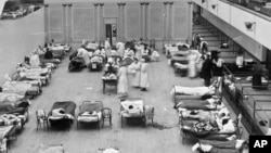 美国国会图书馆提供1918年照片: 美国红十字会的志愿护士在用作临时医院的奥克兰市政厅照顾流感患者。