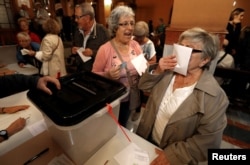 A woman kisses a ballot before voting at a polling station for the banned independence referendum in Barcelona, Spain, Oct. 1, 2017.