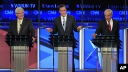 Former Massachusetts Governor Mitt Romney answers a question as former House Speaker Newt Gingrich, left, and Rep. Ron Paul, listen during the first Republican presidential debate in Manchester, New Hampshire, June 13, 2011
