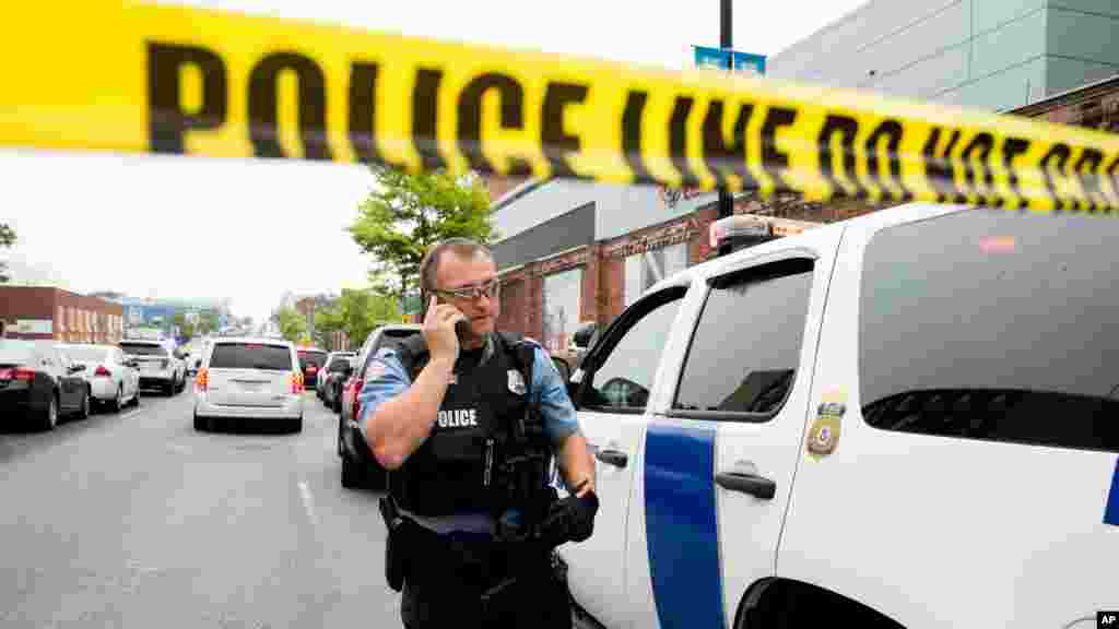 Um oficial de polícia fala ao telemóvel enquanto um grande aparato policial se vai instalando ao longo da rua M no sudeste da capital americana, Washington DC. 2 Julho 2015