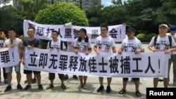 People hold banners at a demonstration in support of factory workers of Jasic Technology, outside Yanziling police station in Pingshan district, Shenzhen, Guangdong province, China, Aug. 6, 2018.