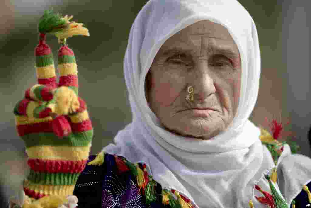 A woman of the Peace Mothers, a Kurdish civil rights group that promotes peace between Turkey's ethnic groups, flashes a victory sign in the village of Caykara, just across the border from Kobani, Syria, Nov. 3, 2014. 