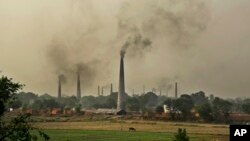 Smoke rises from chimneys of brick kilns on the outskirts of New Delhi, India, June 16, 2015. 