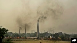 Smoke rises from chimneys of brick kilns on the outskirts of New Delhi, India, June 16, 2015. 