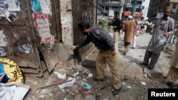 A police officer collects evidence from the site of a bomb blast on University Road in Peshawar, Apr. 29, 2013. 
