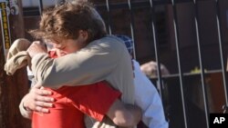 Two people embrace outside a Northern Arizona University student dormitory, Oct. 9, 2015, in Flagstaff, Ariz., after an early morning confrontation between two groups of students escalated into gunfire.