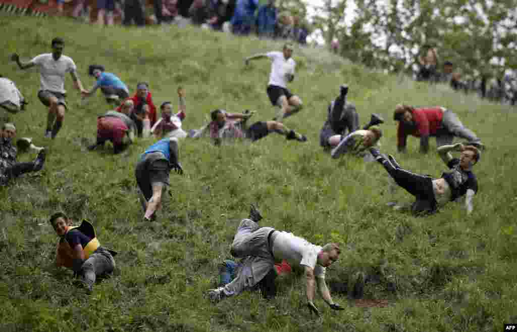 Competitors tumble down Coopers Hill in pursuit of a large wheel of Double Gloucester cheese, during an annual cheese-rolling competition near the village of Brockworth, Gloucester, in western England.