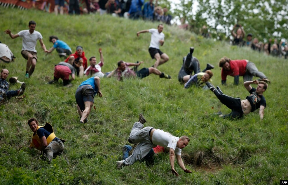 Competitors tumble down Coopers Hill in pursuit of a round Double Gloucester cheese during an annual cheese rolling competition near the village of Brockworth, Gloucester, in western England.