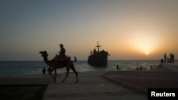 A man rides his camel along the coast, in front of the beached Greek ship Moula F, during sunset off Kish Island, 1,250 km (777 miles) south of Tehran, April 27, 2011. 