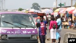 Un jeune garçon du Togo vend de l'eau purifiée à la station de taxis de Libreville le 25 juin 2018.