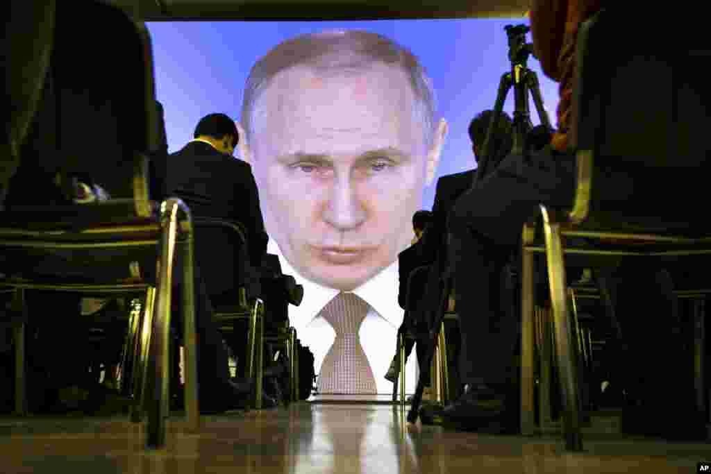 Journalists watch as Russian President Vladimir Putin gives his annual state of the nation address in Manezh in Moscow.