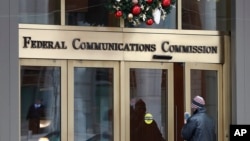 FILE - A person with a smart phone enters the Federal Communications Commission office in Washington on Dec. 14, 2017. The FCC said on Nov. 8, 2024, that its enforcement bureau is investigating racist text messages sent anonymously to Black Americans across the country.