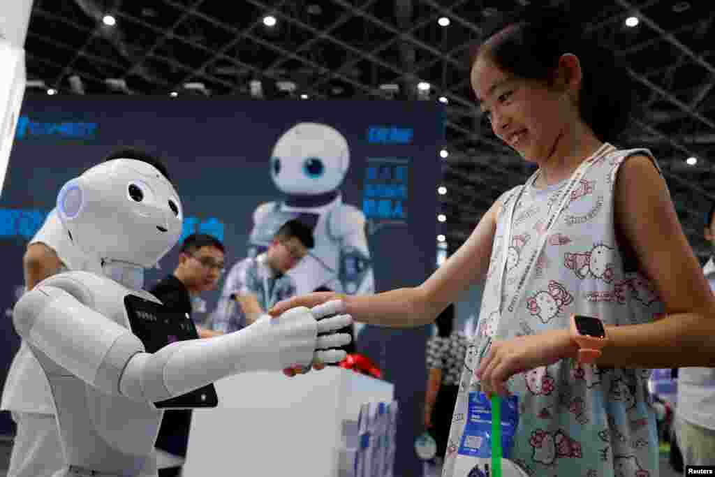 2018年7月4日，上海2018中国国际机器人展览会上，一位访客与机器人握手。
