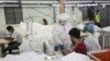 This photo taken on May 8, 2020 shows workers wearing face masks sewing disposable surgical gowns for health workers as protection from the COVID-19 coronavirus at a garment factory in Yangon. - The factory which has switched from making clothes for expor