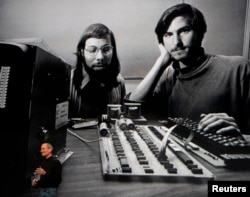 FILE - Apple Chief Executive Officer Steve Jobs stands beneath a photograph of him and Apple-co founder Steve Wozniak from the early days of Apple during the launch of Apple's new "iPad" tablet computing device in San Francisco, California, Jan. 27, 2010.