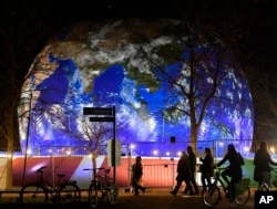 People pass the German pavilion in the shape of the earth during the COP 23 Fiji UN Climate Change Conference in Bonn, Germany, Wednesday evening, Nov. 15, 2017.