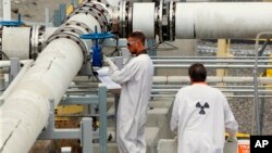 En esta foto de archivo del 9 de julio de 2014, los trabajadores que usan ropa protectora y calzado inspeccionan una válvula en la granja de tanques "C" en la Reserva Nuclear de Hanford, cerca de Richland, Wash.